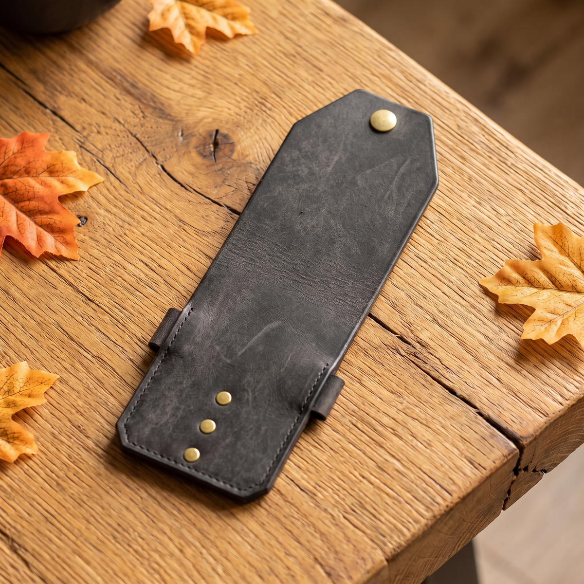 Slim cash clip on a rustic wooden table with fall leaves